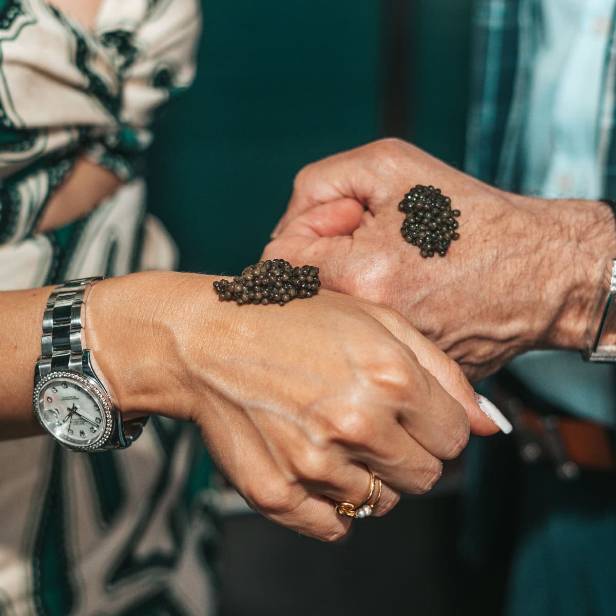 Two hands with caviar on wrist and hand.