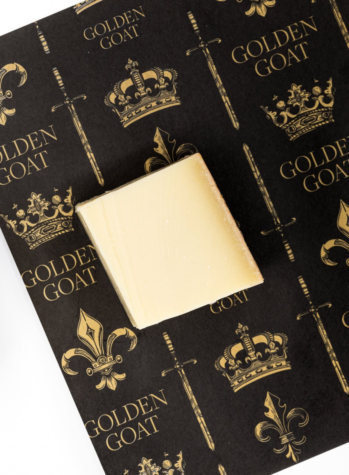 A block of cheese on a black background with a golden goat logo pattern.