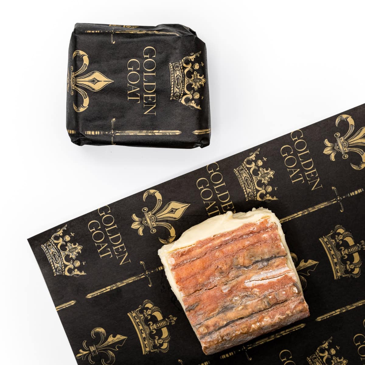 A block of Taleggio cheese with a rind on, placed on a paper packaging with 'GOLDEN GOAT' branding and crown motifs.