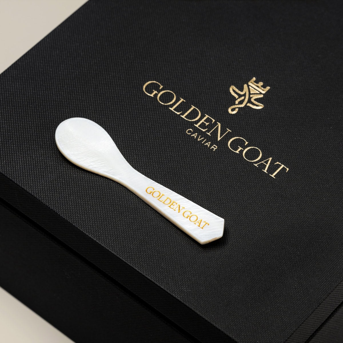 Caviar spoon on a gift box with 'GOLDEN GOAT' etched in the center.