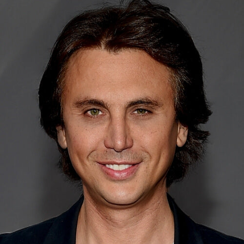 Man with dark hair and a slight smile against a gray background
