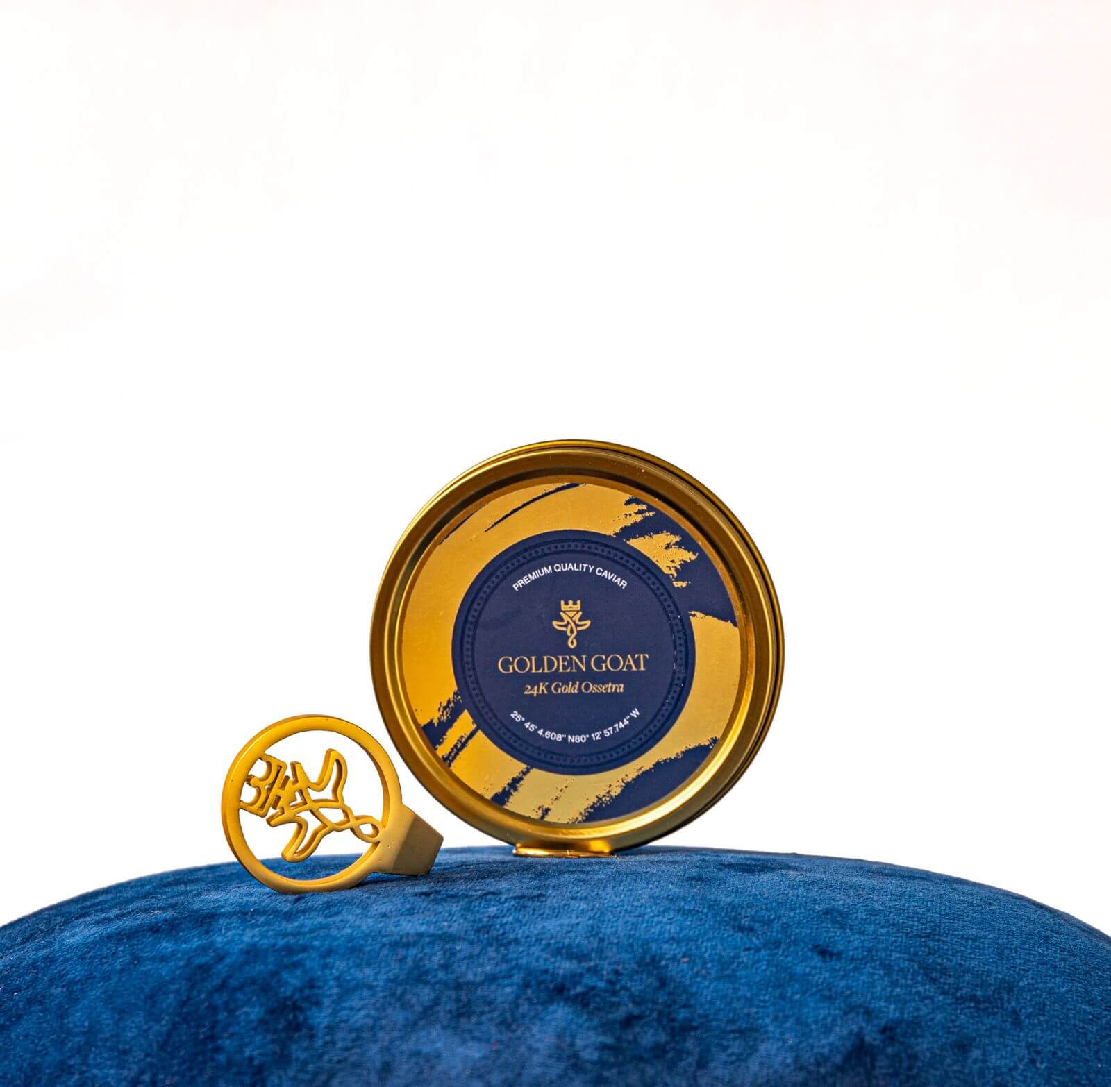 A tin of Golden Goat caviar with a luxury caviar key on a blue velvet cushion.