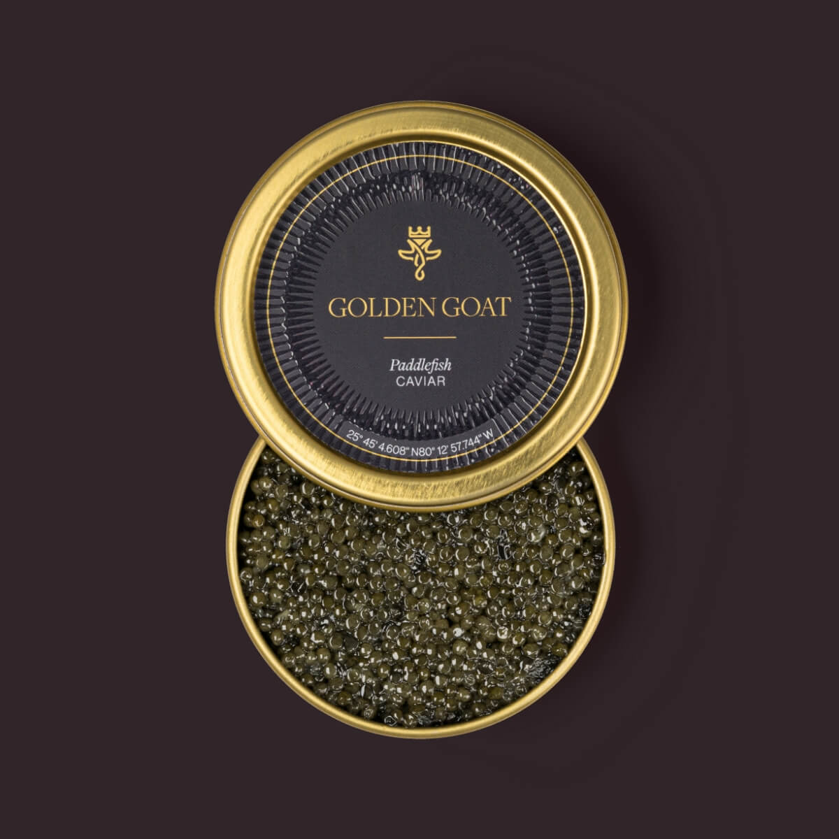 A tin container of paddlefish caviar with the brand 'GOLDEN GOAT' visible on the lid, the caviar is visible as dark, grayish pellets.
