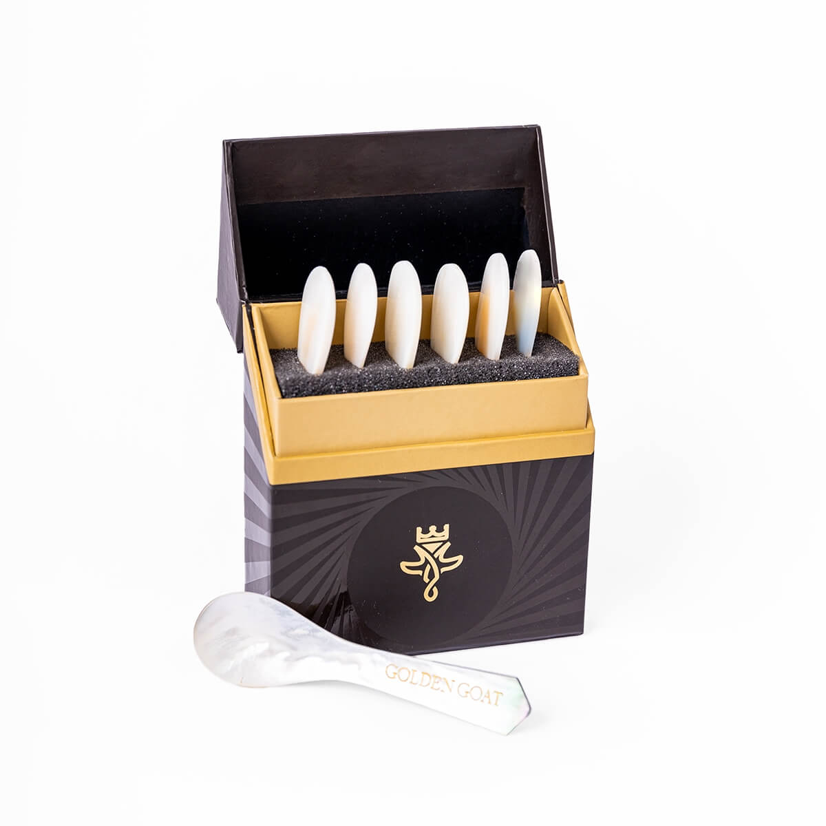 Set of white pearl spoons in a decorative black and gold box with a visible brand logo.