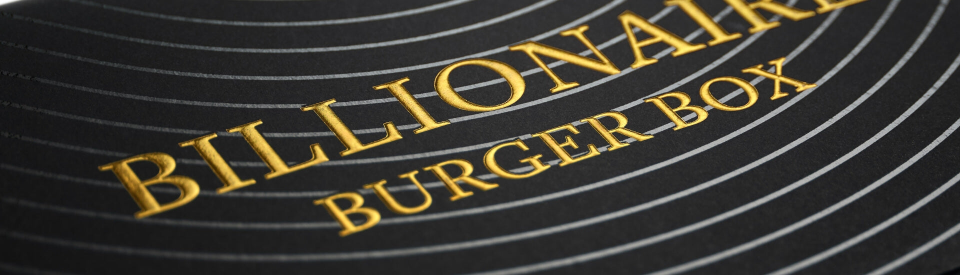 Close-up of a 'Billionaire Burger Box' logo on a textured surface