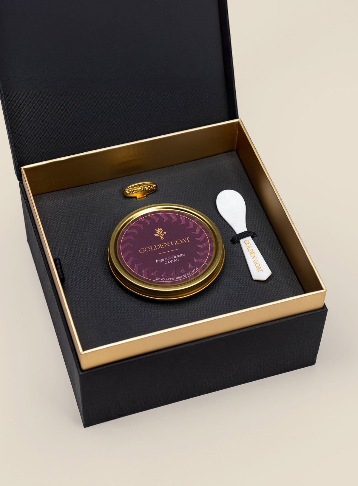 Caviar tin in a gift box with a caviar spoon and tin opener on a beige background.
